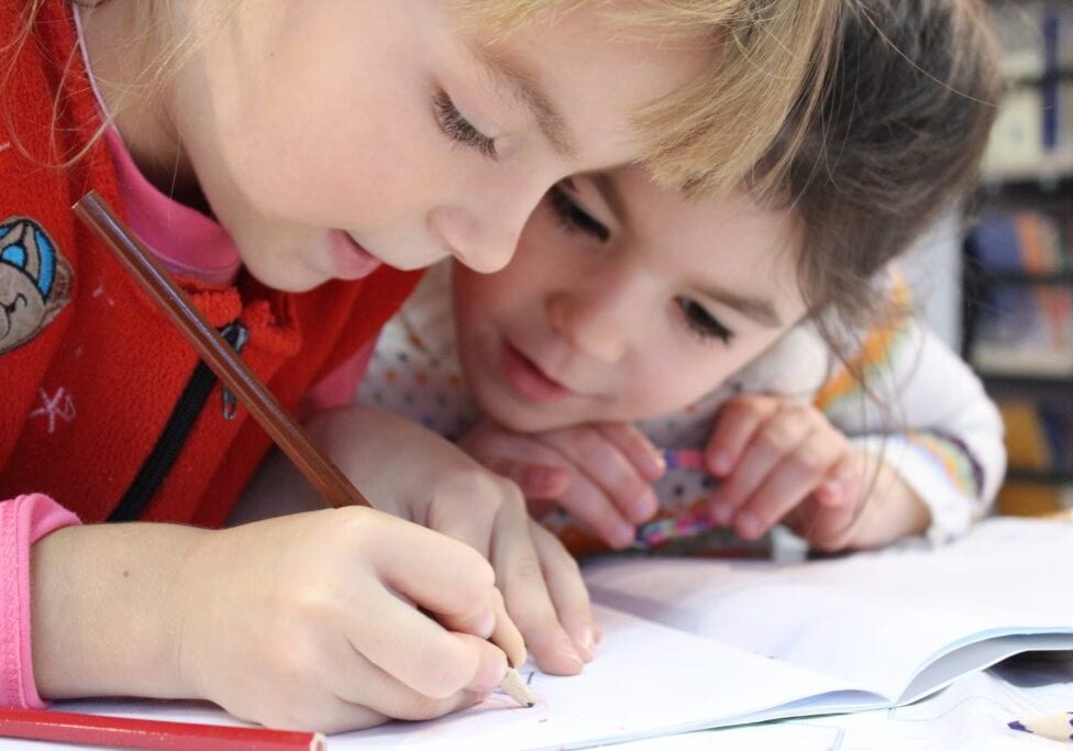 girls-on-desk-looking-at-notebook-159823