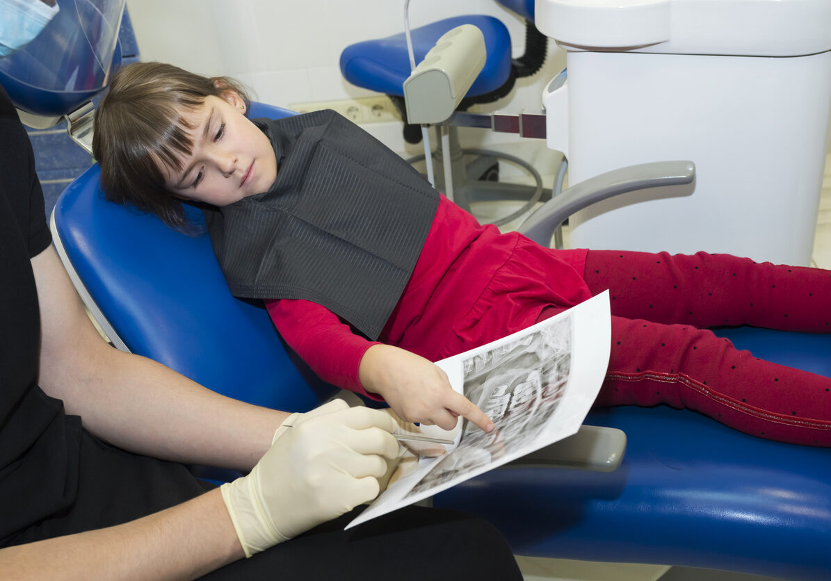 A dentist showing dental X-rays (radiographs) to a patient, a kid.